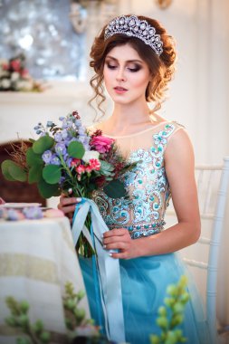 Bir buket çiçek ile bir tablo başına oturmuş bir lüks mavi elbiseli güzel genç bayan