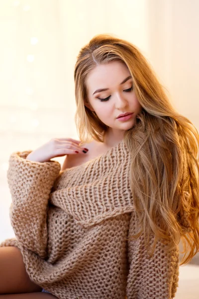 Young blonde woman in a warm pullover in a light bedroom in a morning — Stock Photo, Image