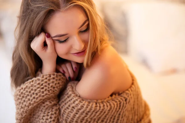 Young blonde woman in a warm pullover in a light bedroom in a morning — Stock Photo, Image