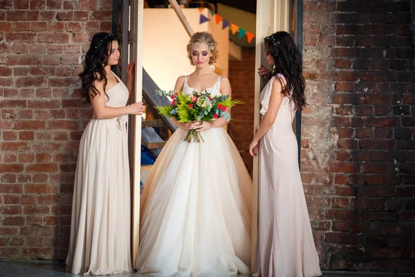 Όμορφη ξανθιά νύφη σε πολυτελές νυφικό και όμορφα δίδυμα παράνυμφων σε παρόμοια φορέματα σε ένα πρωινό σε μια σοφίτα χώρο. Μοντέρνα μοντέρνα γαμήλια φωτογραφία — Φωτογραφία Αρχείου