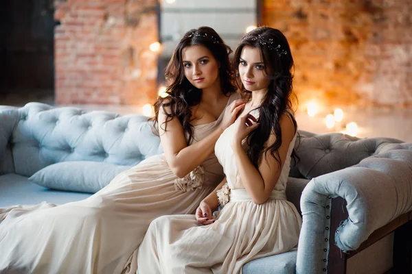 Beautiful twins young women in in gorgeous evening dresses in a loft space in a morning — Stock Photo, Image