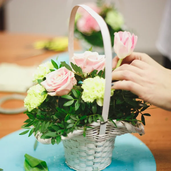 Oficina floral florista faz um buquê em uma cesta. Estudantes floristas trabalham juntos . — Fotografia de Stock