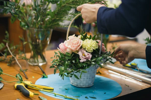 Taller floral - florista hace un ramo en una canasta. Estudiantes floristas trabajan juntos . — Foto de Stock