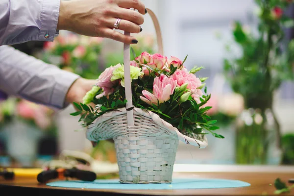 Floral workshop - florist makes a bouquet in a basket. Students florists work together.