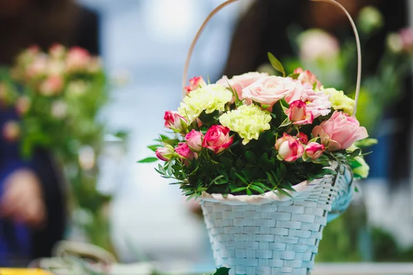 Lugar de trabajo florista: bonito ramo en una canasta sobre un fondo de flores y accesorios. enfoque suave — Foto de Stock