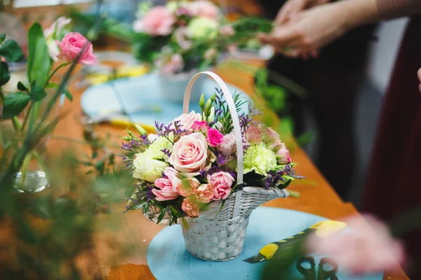 Oficina floral florista faz um buquê em uma cesta. Estudantes floristas trabalham juntos . — Fotografia de Stock