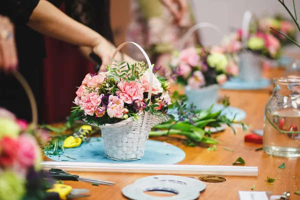 Oficina floral florista faz um buquê em uma cesta. Estudantes floristas trabalham juntos . — Fotografia de Stock