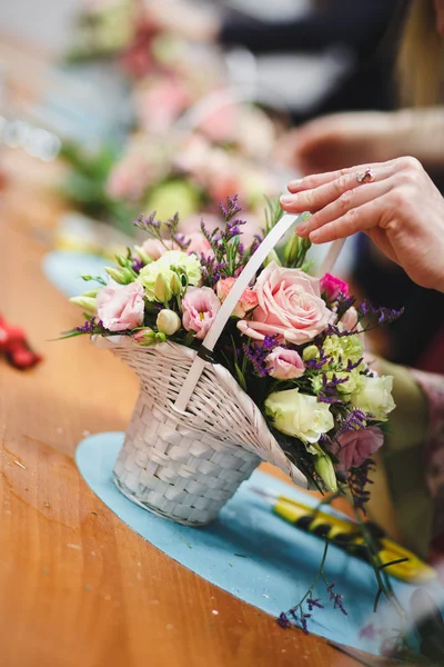 Oficina floral florista faz um buquê em uma cesta. Estudantes floristas trabalham juntos . — Fotografia de Stock