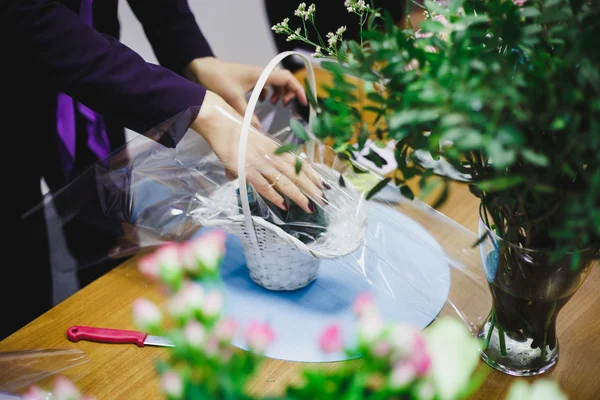 Floral workshop - florist makes a bouquet in a basket. Students florists work together.