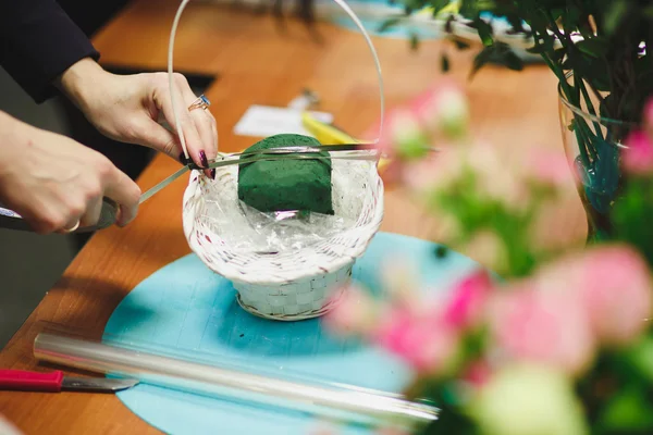 Floral workshop - florist makes a bouquet in a basket. Students florists work together.