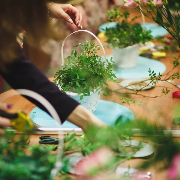 Taller floral - florista hace un ramo en una canasta. Estudiantes floristas trabajan juntos . — Foto de Stock