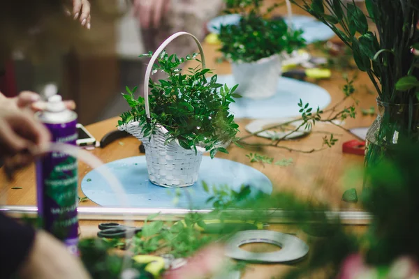 Taller floral - florista hace un ramo en una canasta. Estudiantes floristas trabajan juntos . — Foto de Stock