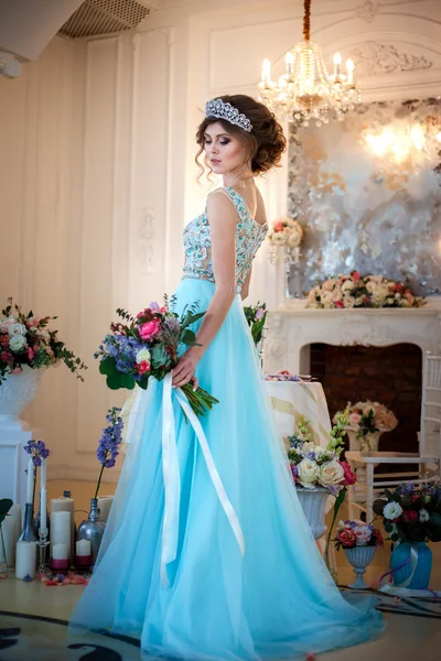 Piękna panienka w luksus niebieski strój w eleganckie wnętrza z bukietem kwiatów — Zdjęcie stockowe