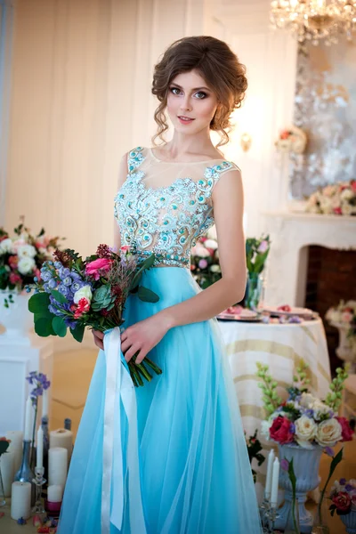 Bir lüks mavi güzel genç bayan elbise bir buket çiçek ile zarif iç