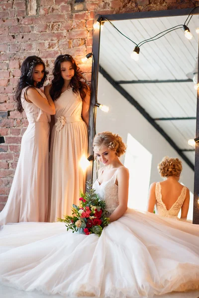 豪華なウェディングドレスで美しいブロンドの花嫁とランプの鏡と花輪とロフトスペースで朝に似たようなドレスでかわいい双子の花嫁介添人。ファッションモダンな結婚式の写真. ストックフォト