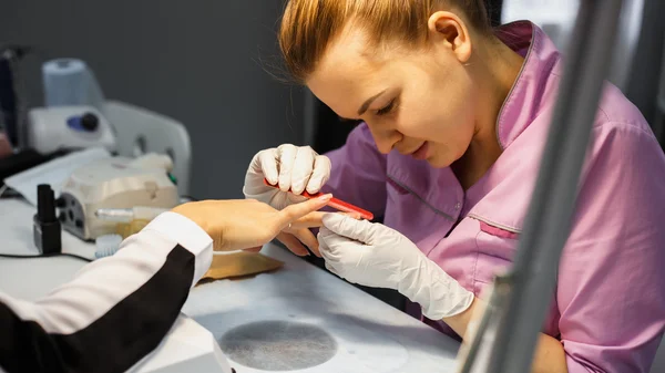 Procedimiento de cuidado de la manicura, foto de cerca de la mano esteticista limado uñas de la mujer en el salón — Foto de Stock