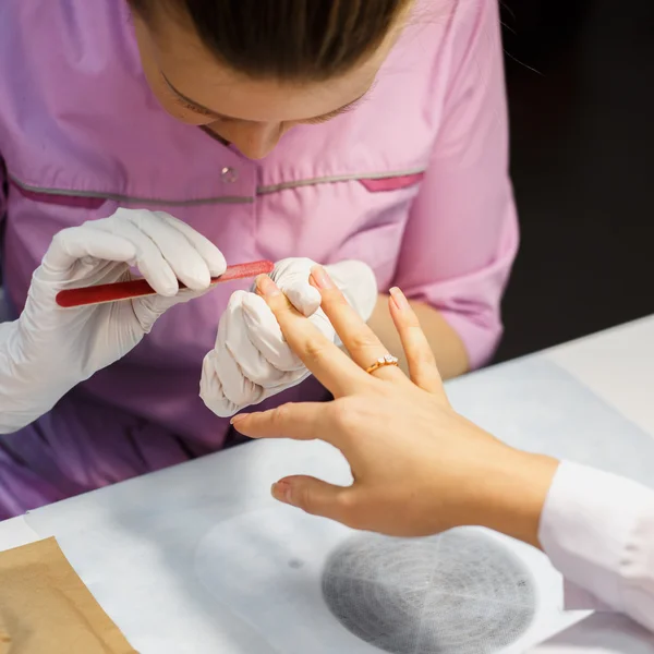 Procedimiento de cuidado de la manicura, foto de cerca de la mano esteticista limado uñas de la mujer en el salón — Foto de Stock