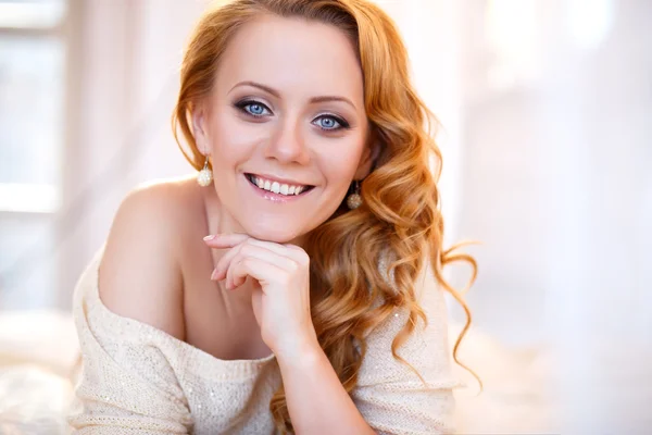 Young beautiful woman in a warm pullover in a light bedroom in a morning. Close up portrait, blue eyes and natural makeup — Stock Photo, Image