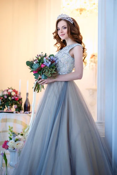 Menina bonita em um vestido de luxo em interior elegante com um buquê de flores — Fotografia de Stock