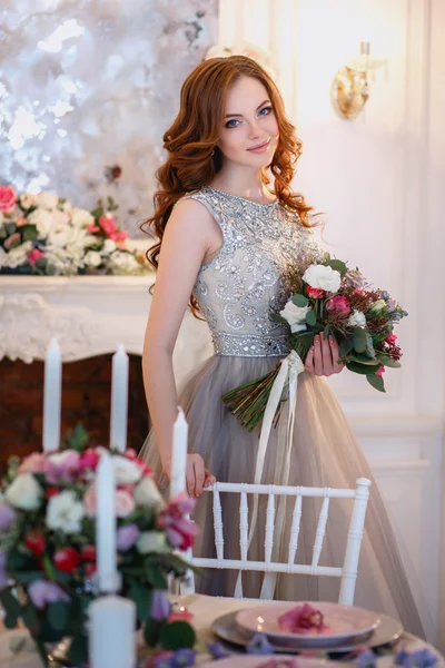 Menina bonita em um vestido de luxo em interior elegante com um buquê de flores — Fotografia de Stock