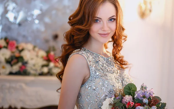 Gyönyörű fiatal hölgy egy luxus ruha elegáns belső tér egy csokor virág — Stock Fotó