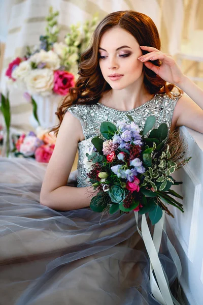 Menina bonita em um vestido de luxo em interior elegante com um buquê de flores — Fotografia de Stock