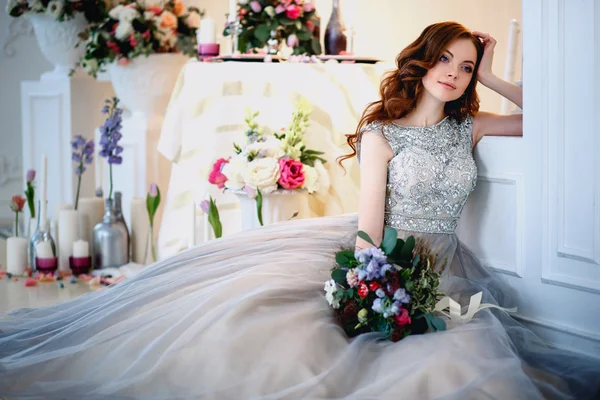 美丽的年轻女士在优雅的内部与一束鲜花的豪华礼服 — 图库照片