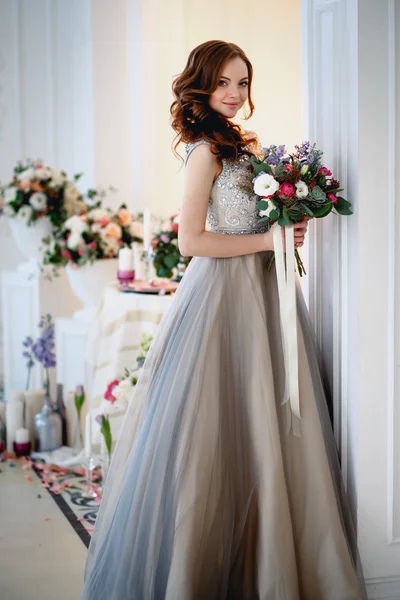 Красивая юная леди в роскошном платье в элегантном интерьере с букетом цветов — стоковое фото