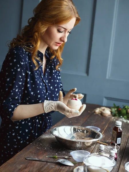 Mujer joven prepara bombas de baño. Ingredientes y decoración floral en una mesa vintage de madera . — Foto de Stock