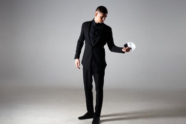 Yakışıklı adam sihirbaz siyah elbiseli kartları bir elinde tutan bir portresi