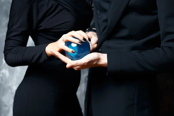 Magician young man and his assistant woman in a black clothes hold a magical sphere — Stock Photo, Image