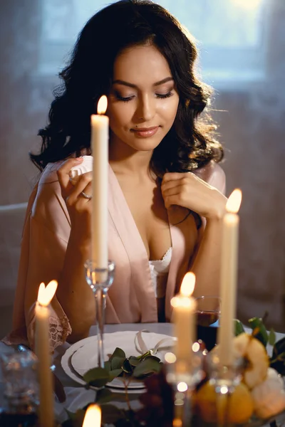 Primer plano retrato de la hermosa novia morena antes de la boda, sentado junto a una mesa con decoración y velas — Foto de Stock