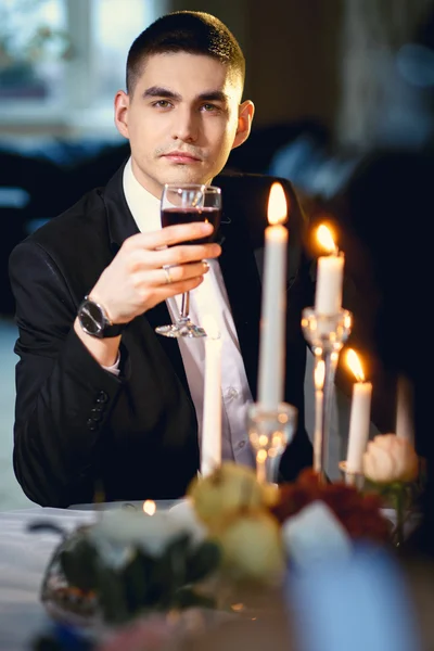 Retrato de primer plano del novio guapo, sentado junto a una mesa con decoración y velas — Foto de Stock