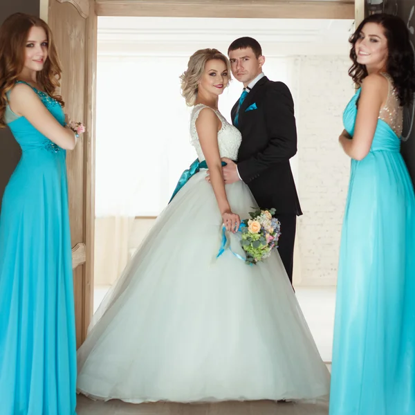 Novia, novio y tres damas de honor en vestidos azules similares con maquillaje perfecto y estilo de pelo en un espacio loft luz —  Fotos de Stock