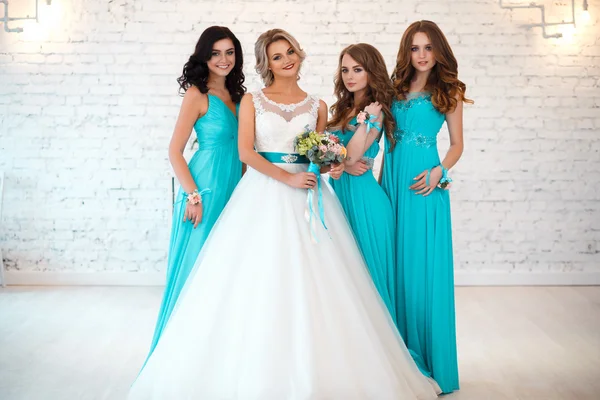 Novia y tres damas de honor en vestidos azules similares con maquillaje perfecto y estilo de pelo en un espacio loft luz —  Fotos de Stock