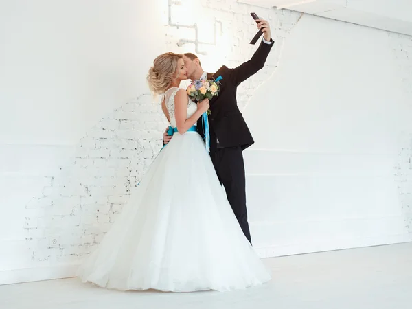 Noiva elegante e noivo juntos em um dia de casamento em um espaço loft moderno fazendo foto por telefone celular — Fotografia de Stock