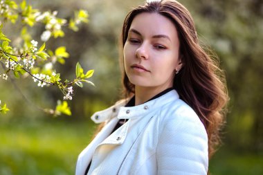 bir yaz bahçesinde ağaçlar çiçek açan genç kadın yürüyor