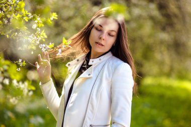 bir yaz bahçesinde ağaçlar çiçek açan genç kadın yürüyor