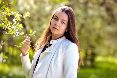 bir yaz bahçesinde ağaçlar çiçek açan genç kadın yürüyor