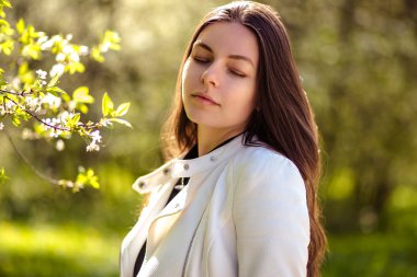 bir yaz bahçesinde ağaçlar çiçek açan genç kadın yürüyor