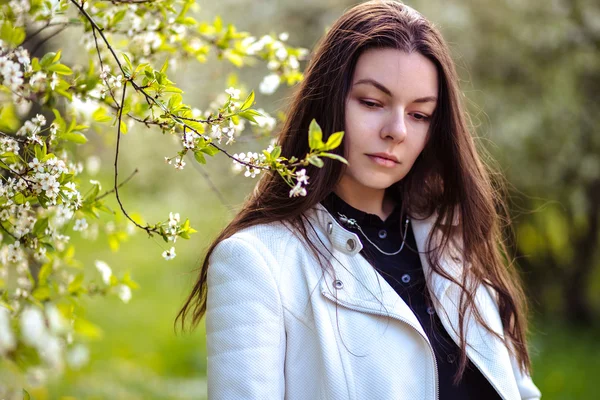 bir yaz bahçesinde ağaçlar çiçek açan genç kadın yürüyor