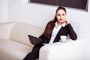 Kadın kahve içer ve bir tablet bilgisayarda office lounge bölgedeki İnşaat