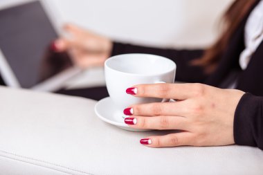 Kadın kahve içer ve bir tablet bilgisayarda office lounge bölgedeki İnşaat
