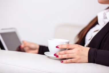 Kadın kahve içer ve bir tablet bilgisayarda office lounge bölgedeki İnşaat