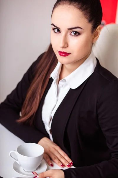 Beautiful modern businesswoman in her office with a cup of coffee — Stock Photo, Image