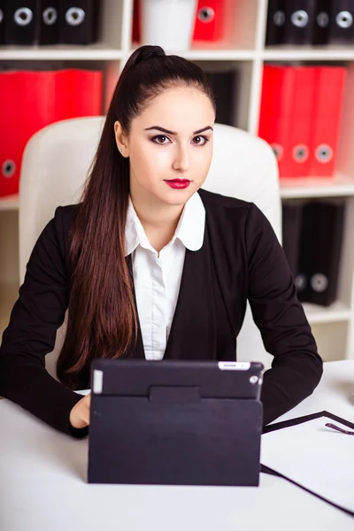 Красива сучасна бізнес-леді в її офісі з паперовою текою і планшетним комп'ютером і мобільним телефоном — стокове фото