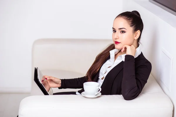 Mulher bebe café e trabalha em um computador tablet na zona lounge do escritório — Fotografia de Stock