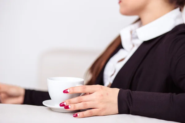 Mujer bebe café y trabaja en una tableta en la zona de salón de la oficina — Foto de Stock