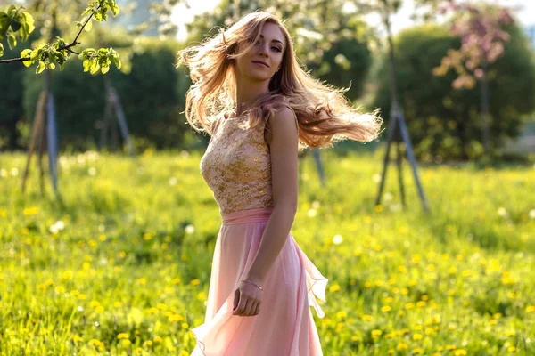 Krásná mladá žena v letních šatech poblíž kvetoucí stromy — Stock fotografie