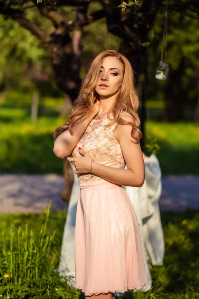 Gyönyörű fiatal nő, egy nyári ruha, virágzó fák közelében. Dekoratív zóna egy parkban — Stock Fotó